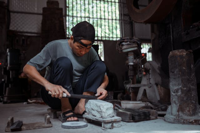  A person carefully sharpening a Japanese knife on a whetstone with water droplets on the stone.